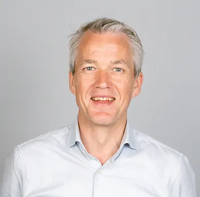 CEO at TAGARNO, Søren Schultz, in white shirt smiling at the camera in front of a grey wall, classic employee photo