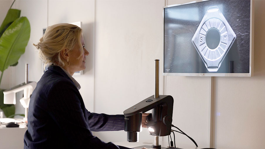 Woman using a multifunctional digital microscope to inspect metal parts