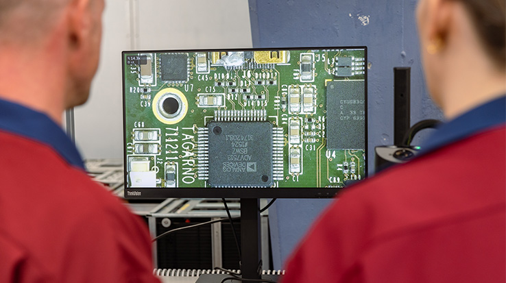 Over the shoulder shot of two employees at an EMS using a digital microscope to inspect their PCBs