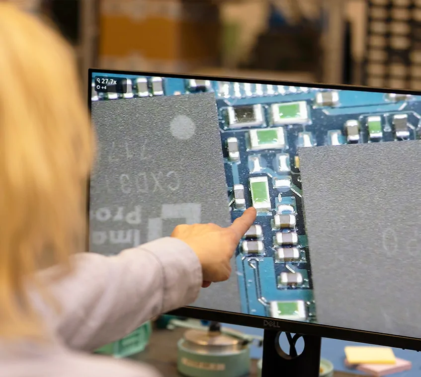 Woman pointing at a monitor with a magnified PCB