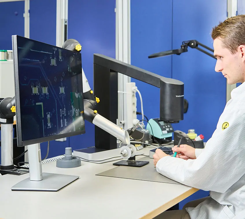 Man using a TAGARNO T50 microscope to solder PCBs