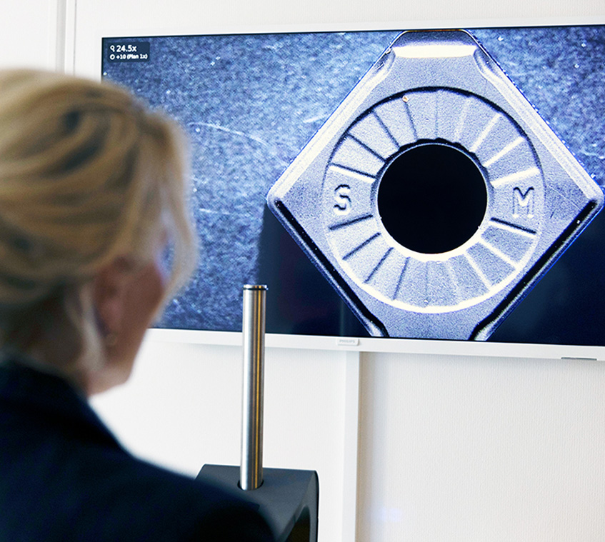 Over the shoulder shot of woman using a digital microscope to look at bolts on a monitor